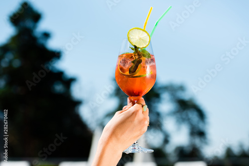 Cropped view of woman holding cocktail with mint and lemon on resort