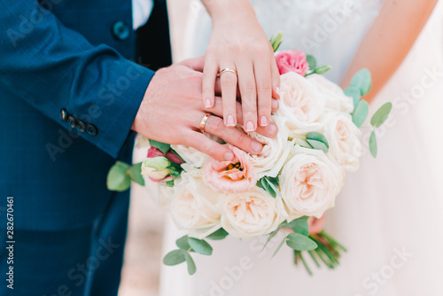 Foto Hands of bride and groom with wedding rings on beautiful bouquet of roses