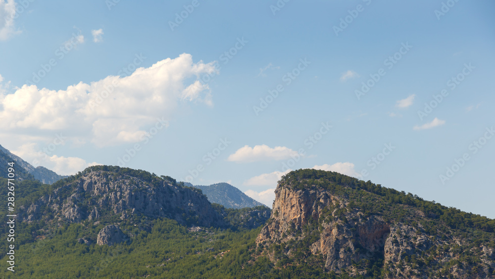 Beautiful landscape in the mountains. Lovely view of the Taurus Mountains against the blue sky and clouds. Soft sunlight falls on the mountain tops. Kemer, Turkey. Postcard view