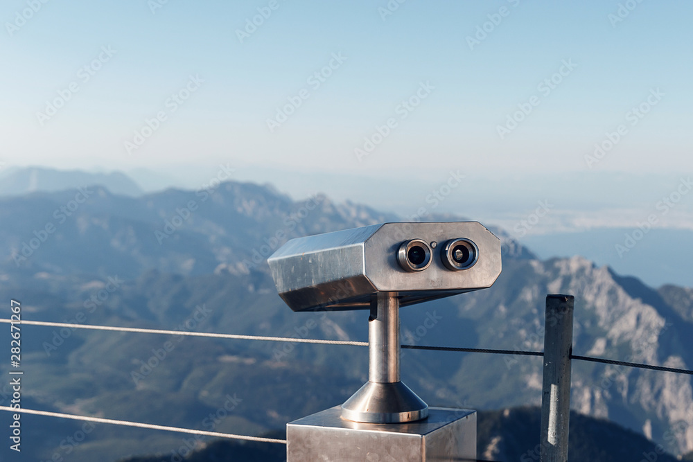 Stationary binoculars or binoscope on the viewing platform against the background beautiful landscape in the mountains. Lovely view of the Taurus Mountains and the Mediterranean coast. Kemer, Turkey
