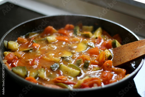 Cooking vegetables in a pan: zucchini, tomato and carrot. Selective focus.