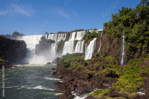 Beautiful view of waterfalls on Iguazu river in sunny summer day. Foz de iguaçu divides the border between Brazil and Argentina and is One of the Seven Wonders of the World.