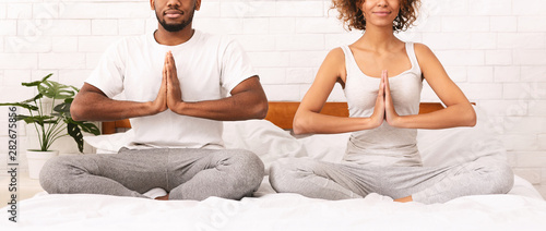 Young black family meditating in bed together