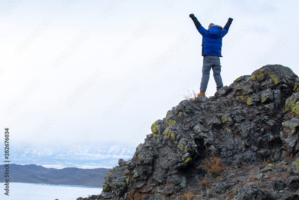 Man put his hands up on top of mountain, Lake Bikal in Russia