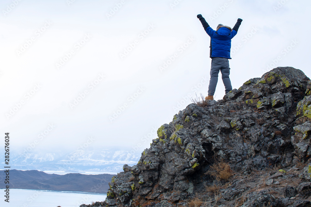 Man put his hands up on top of mountain, Lake Bikal in Russia Man put his hands up on top of mountain, Lake Bikal in Russia