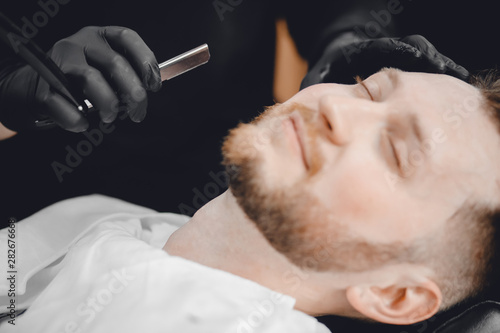 Barbershop. Hairdressers barber hair and beard with razor in salon