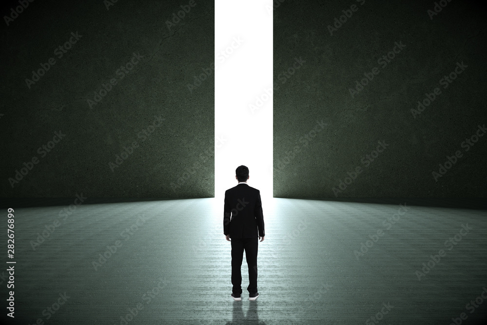 Obraz premium Businessman standing in a dark room and looking outside