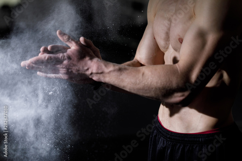 Cropped shot of muscular caucasian sportsman applying talcum powder on hands © proimagecontent