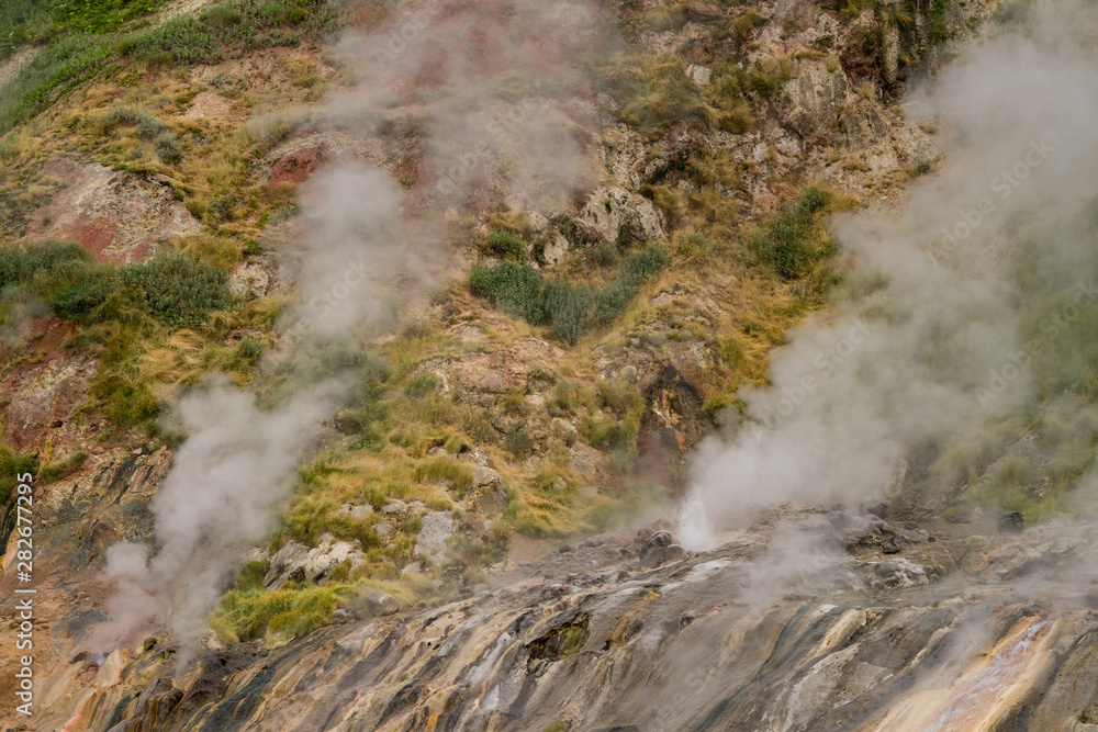 Valley of Geysers in Kronotsky Nature Reserve. Geyser field on Kamchatka Peninsula, Russia. Slope descending to Geysernaya River, steaming hot springs, mud volcanoes, colorful clay, geothermal waters Valley of Geysers in Kronotsky Nature Reserve. Geyser field on Kamchatka Peninsula, Russia. Slope descending to Geysernaya River, steaming hot springs, mud volcanoes, colorful clay, geothermal waters