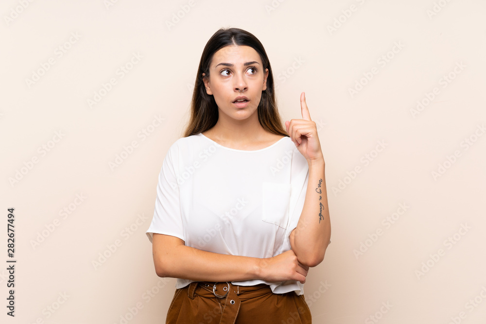 Obraz premium Young brunette woman over isolated background thinking an idea pointing the finger up
