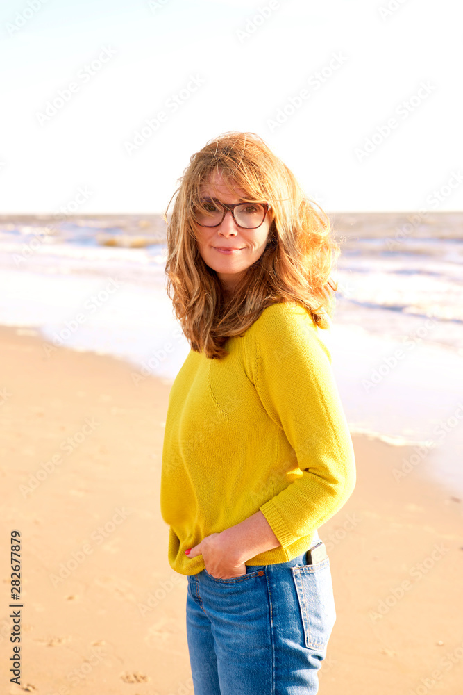 Middle aged woman with frizzy hair walking on the beach Middle aged woman with frizzy hair walking on the beach