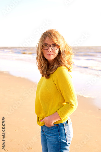 Middle aged woman with frizzy hair walking on the beach