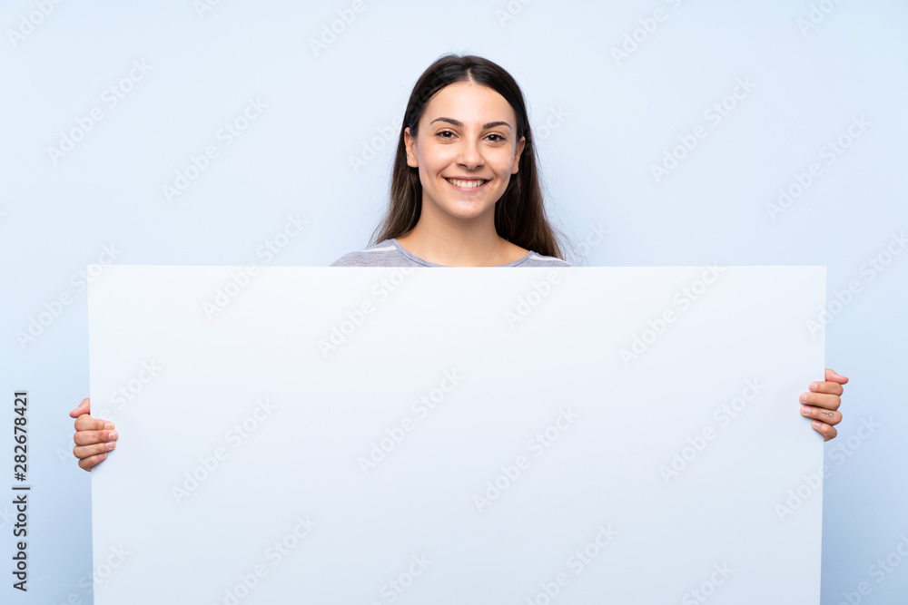 Young brunette woman over isolated blue background holding an empty white placard for insert a concept Young brunette woman over isolated blue background holding an empty white placard for insert a concept