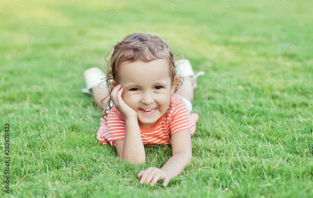 Portrait of a smiling little girl lying on green grass. Portrait of a smiling little girl lying on green grass.