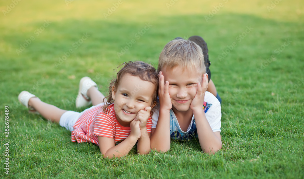 Portrait of a smiling little girl and boy lying on green grass. Portrait of a smiling little girl and boy lying on green grass.