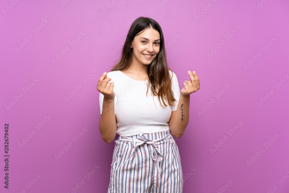 Young woman over isolated purple background making money gesture Young woman over isolated purple background making money gesture