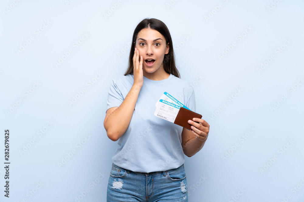 Traveler woman with boarding pass over isolated blue wall with surprise and shocked facial expression Traveler woman with boarding pass over isolated blue wall with surprise and shocked facial expression