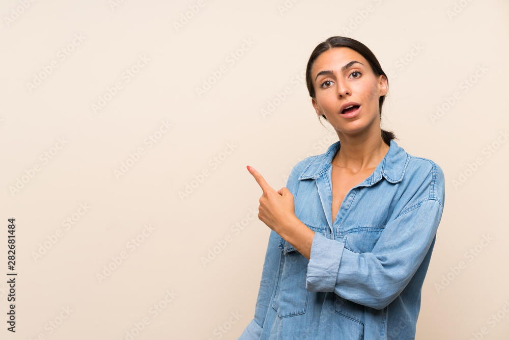 Young woman over isolated background surprised and pointing side Young woman over isolated background surprised and pointing side