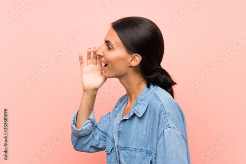 Young woman over isolated pink background shouting with mouth wide open