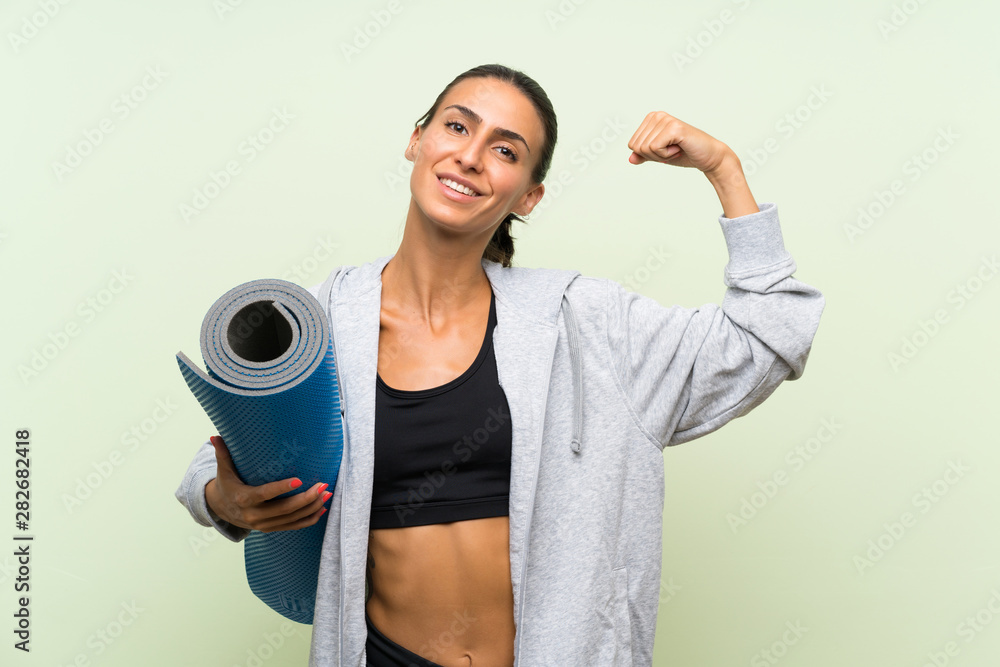 Young sport woman with mat over isolated green background Young sport woman with mat over isolated green background