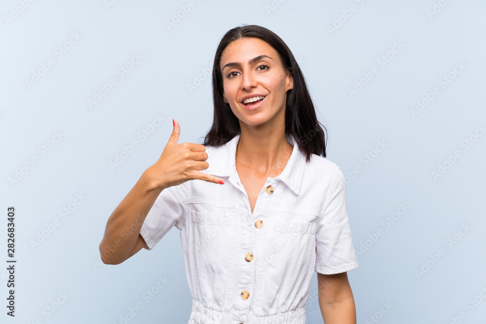 Young woman over isolated blue background making phone gesture Young woman over isolated blue background making phone gesture