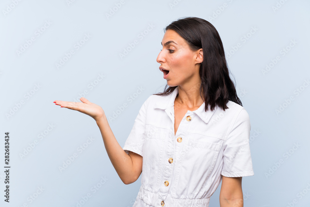 Young woman over isolated blue background holding copyspace imaginary on the palm Young woman over isolated blue background holding copyspace imaginary on the palm