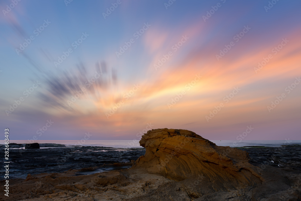Daybreak at the rocky coast of La Mata near the Spanish port city Torrevieja. A long exposure with very nice soft and colored clouds in the sky.