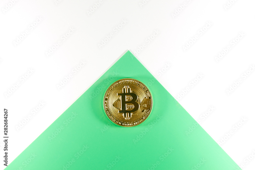 Physical gold bitcoin coin on a green white envelope. Digital cryptocurrency concept Physical gold bitcoin coin on a green white envelope. Digital cryptocurrency concept