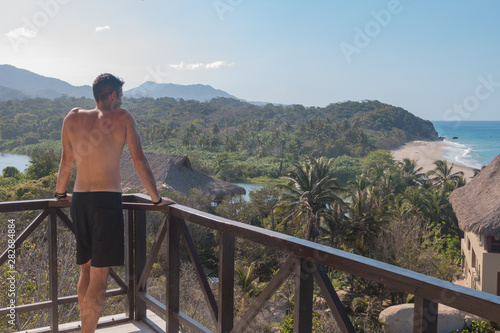 Junger Mann genießt die Aussicht von seinem Balkon auf den Tayrona Nationalpark in Kolumbien