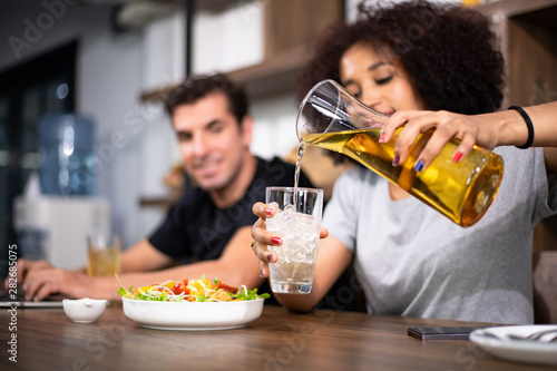 Young couple is feeding each other and smiling while cooking salad and hamburger in kitchen