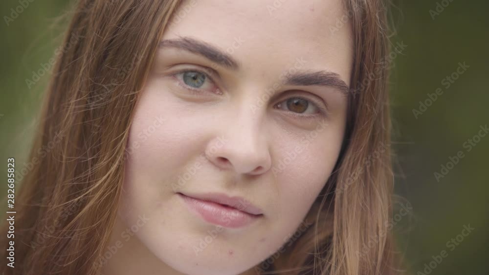 Close-up portrait of pretty carefree young woman with different colored eyes looking at camera indoors. Happy caucasian woman greets new day. Leisure, day off at home. Real people series. Close-up portrait of pretty carefree young woman with different colored eyes looking at camera indoors. Happy caucasian woman greets new day. Leisure, day off at home. Real people series.