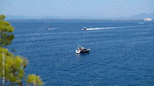 Motor boats sail on the sea on calm water in the sunny day, along the coast of the Mediterranean. Water activities, summer time, happy holidays in the sea concept. Seascape from the mountains. © Olga