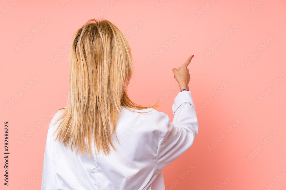 Young blonde doctor woman pointing back with the index finger Young blonde doctor woman pointing back with the index finger