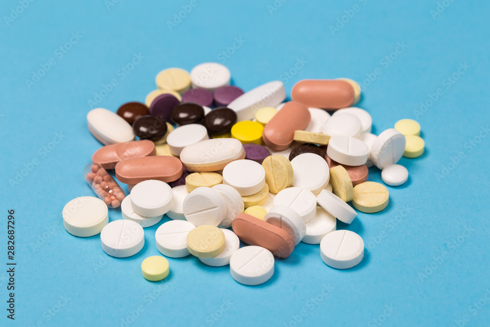 many scattered Colorful medical pills on pastel blue background many scattered Colorful medical pills on pastel blue background