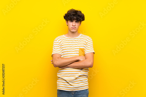 Young man over isolated yellow wall feeling upset