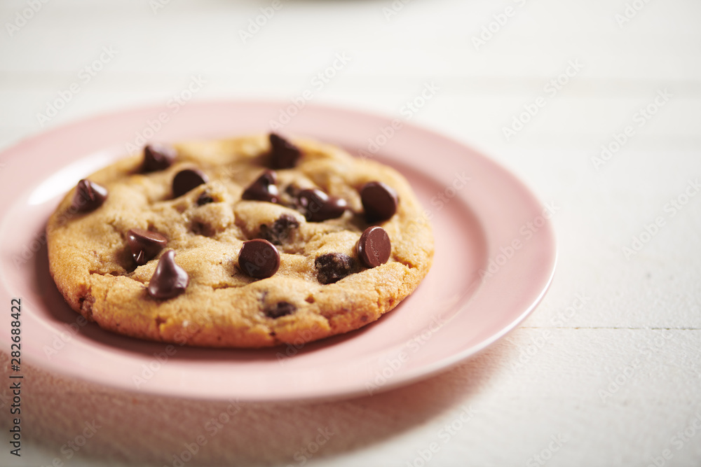Chocolate Chip Cookie on Pink Plate and Rustic White Surface Chocolate Chip Cookie on Pink Plate and Rustic White Surface