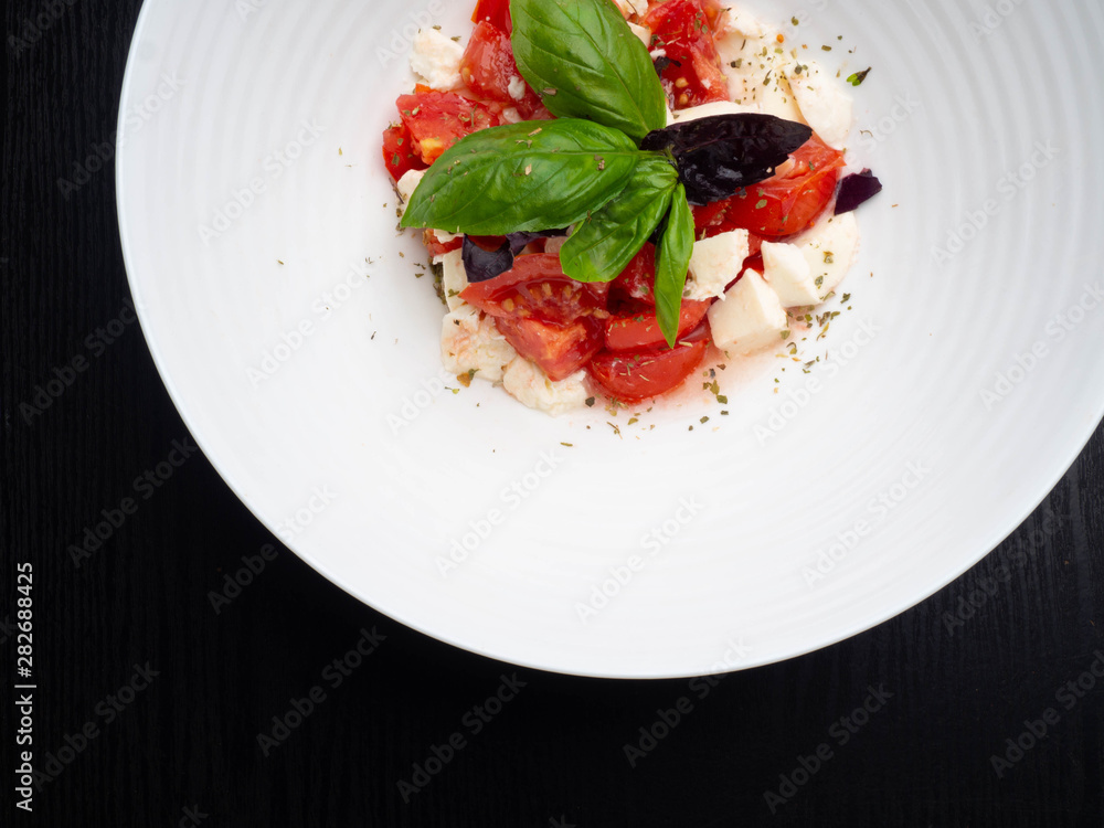 Delicious caprese salad with ripe tomatoes and mozzarella cheese with fresh basil leaves. Italian food. Delicious caprese salad with ripe tomatoes and mozzarella cheese with fresh basil leaves. Italian food.