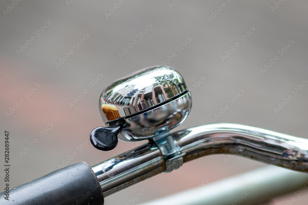 Obraz premium Verchromte und glänzend-polierte Fahrradklingel mit schöner Spiegelung vor unscharfem Hintergrund lädt zum Radfahren und umweltfreundlichen Radeln ein