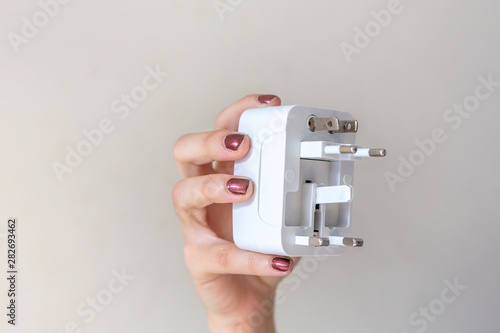 Close up of woman hand holding universal electric socket plug adapters, isolated on white background. Used to connect electrical outlets worldwide. Concept of sollution, travel and technology.