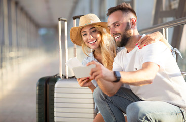 Couple using phone, making video call in airport