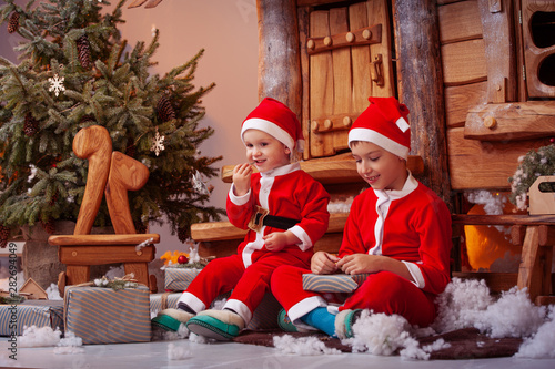 A group of four children in a Christmas hat and costumes with gifts near a fabulous house