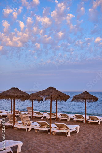 Sun umbrellas and sunbeds facing the sea one summer afternoon