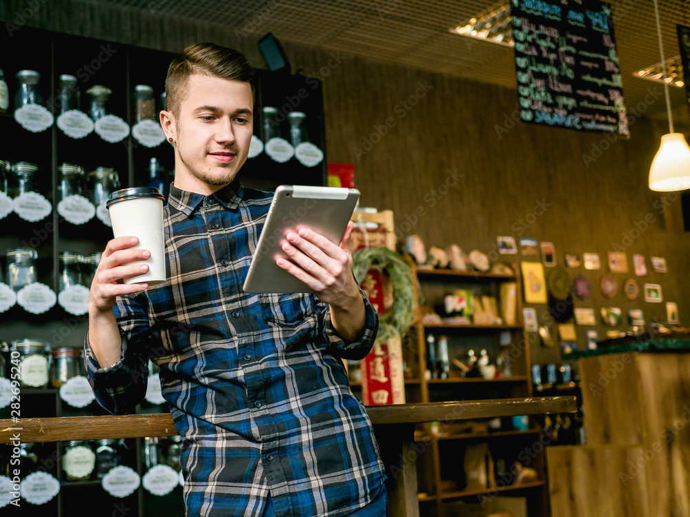guy with coffee paper cup and tablet in cafe 