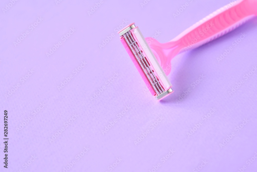 New pink disposable razors for safe shaving of female skin with selective focus on purple background with copy space. Razor for smooth shaving. Sharp razors for personal hygienic routine New pink disposable razors for safe shaving of female skin with selective focus on purple background with copy space. Razor for smooth shaving. Sharp razors for personal hygienic routine