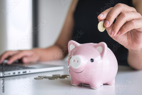 Woman putting golden coin in pink piggy bank for step up growing business to profit and saving with piggy bank, Saving money for future plan and retirement fund concept
