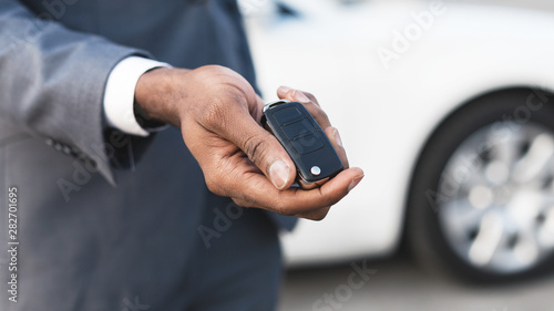 Afro man holding keys with white auto on background