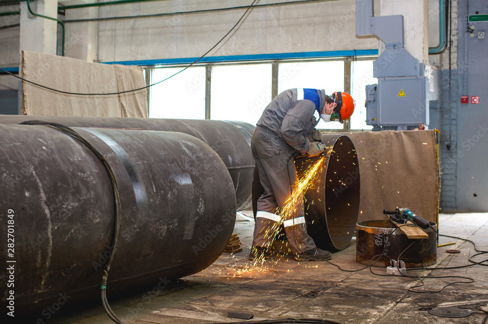 Fitter processes pipe edge with electric hand grinder Fitter processes pipe edge with electric hand grinder