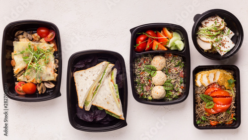 Healthy food in black delivery boxes for lunch in office on white