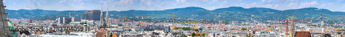 Aerial panoramic cityscape view of austrian capital city of Vienna from the Northern tower Saint Stephen's cathedral. Summertime sunshine day, small cumulus clouds in the blue sky.