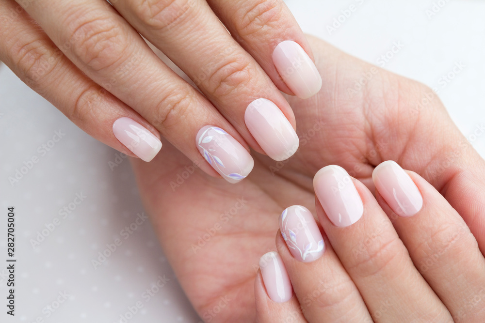 Beautiful groomed woman's hands with feminine nails on the light gray background. Beautiful groomed woman's hands with feminine nails on the light gray background.